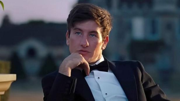 Barry Keoghan sitzt in einem schwarzen Anzug mit Fliege vor einer Villa