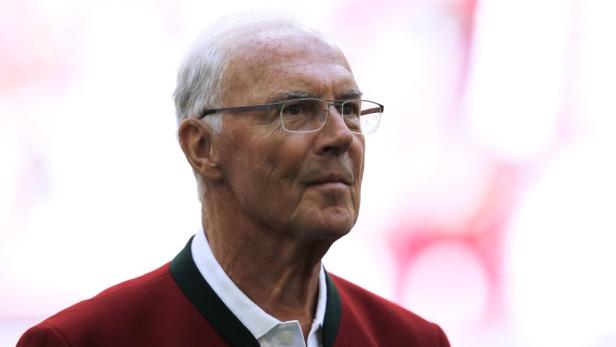 Franz Beckenbauer mit Brille und roter Jacke.