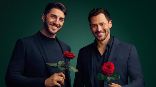 Zwei Männer mit einem charmanten Lächeln, schwarzem Anzug und jeweils einer roten Rose. 