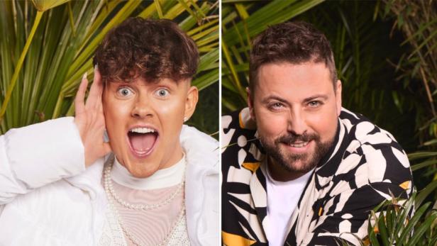 Ein junger Mann mit offenem Mund und ein bärtiger Mann lächeln vor Dschungelkulisse.