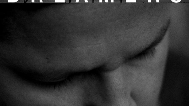 Das Filmplakat für „Dreamers“ zeigt einen Mann vor einem Zaun mit Stacheldraht.