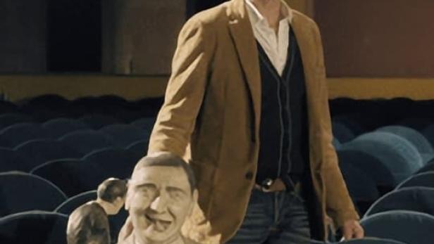 Ein Mann steht in einem leeren Theatersaal hinter einer Pappfigur von Groucho Marx.
