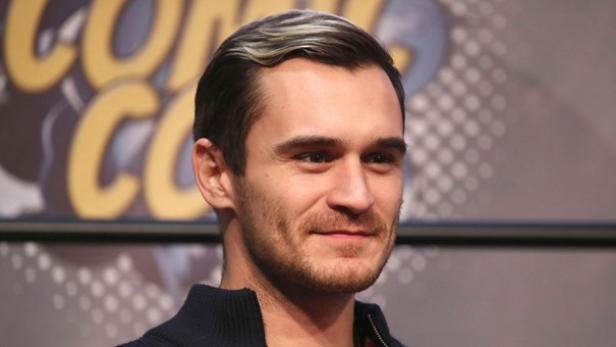 In der nächsten Staffel von "The White Lotus" unverhofft dabei: Schauspieler Julian Kostov. Ein blonder Mann lächelt; er trägt ein schwarzes Hemd