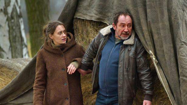 Eine Frau und ein Mann stehen vor einem notdürftigen Zelt im Freien.