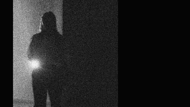 Das Filmplakat für „Un Movimiento Extraño“ zeigt eine dunkle, körnige Silhouette vor einer Wand.