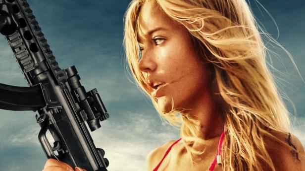 Eine Frau im Bikini hält ein Gewehr vor dem Hintergrund des Filmplakats „Escape“.