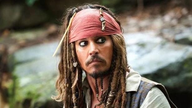 Johnny Depp als Captain Jack Sparrow mit rotem Kopftuch, Rastalocken, weißen Hemd und einem verstörten Blick zur Seite
