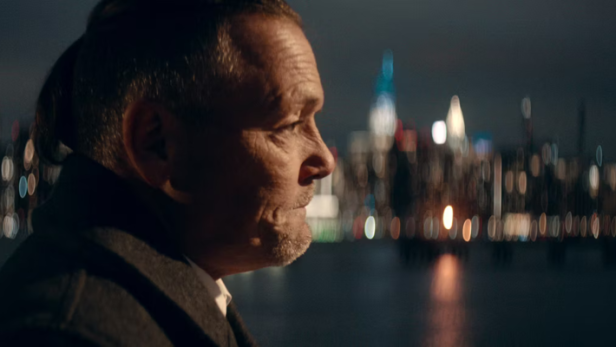 Ein Mann steht vor der abendlichen Kulisse von New York City
