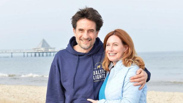 Ein lächelndes Paar steht am Strand von Binz auf Rügen.