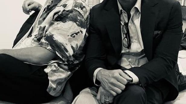 Ein Schwarzweißfoto von zwei Männern, die nebeneinander sitzen.