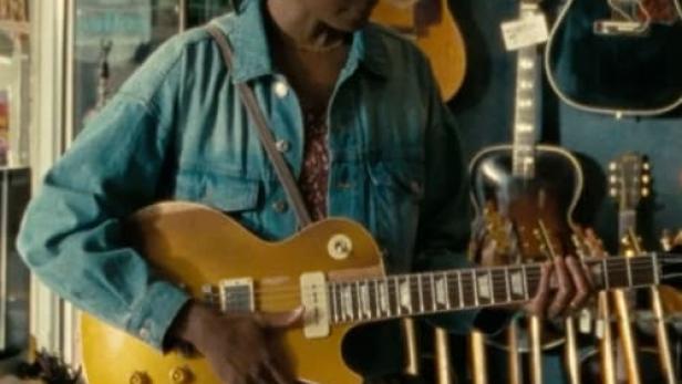 Eine junge Frau spielt in einem Musikgeschäft auf einer gelben E-Gitarre.