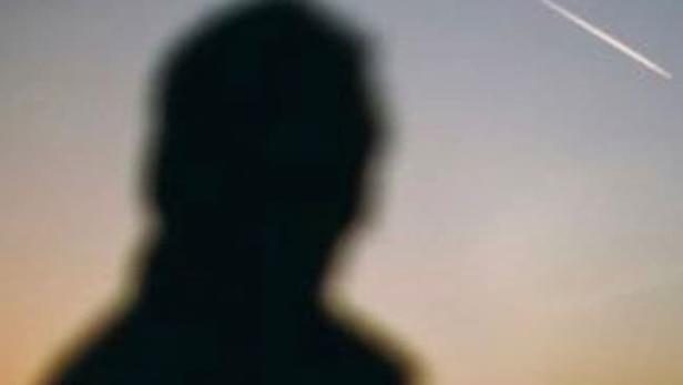 Die Silhouette einer Person vor einem Himmel mit einer Sternschnuppe.