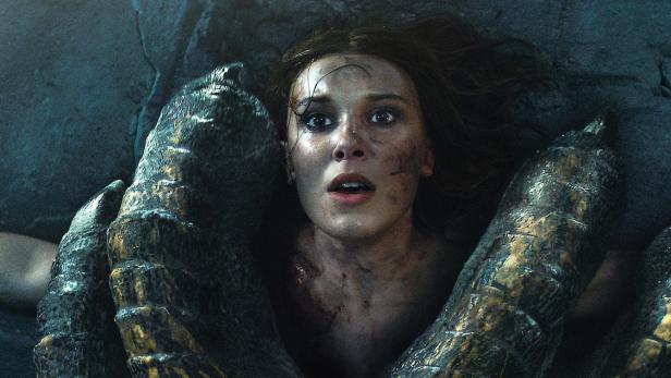 Eine junge Frau liegt verängstigt unter den Krallen eines Drachen.