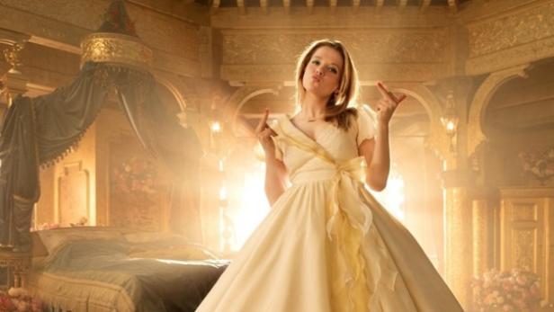 Jella Haase steht in einem gelben Prinzessinnen-Kleid in einem Schlosszimmer. Gelbes Licht erfüllt das Zimmer.