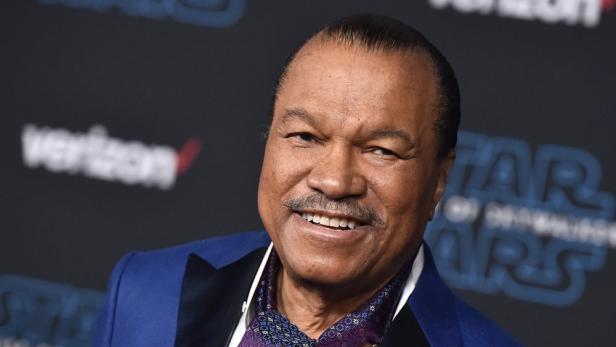Billy Dee Williams posiert vor einem „Star Wars“-Hintergrund.