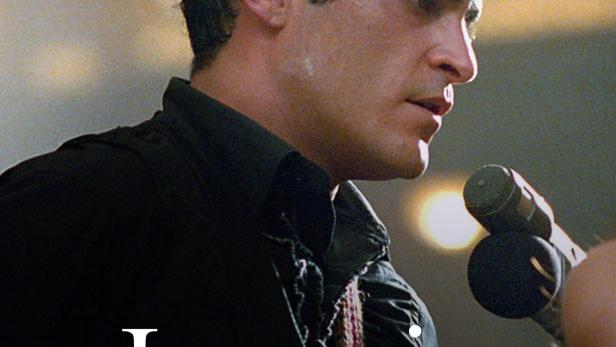 Joaquin Phoenix steht vor einem Mikrofon.