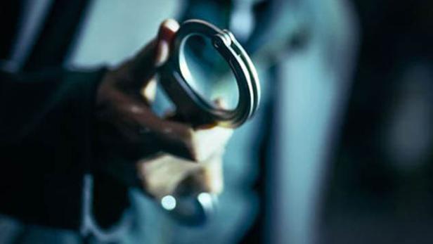 Ein Mann hält eine geöffnete Handschelle in der Hand, im Vordergrund der Titel „I, The Executioner“.