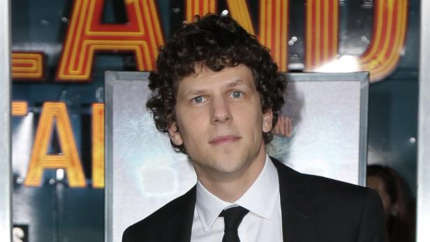 Jesse Eisenberg posiert auf einem roten Teppich.