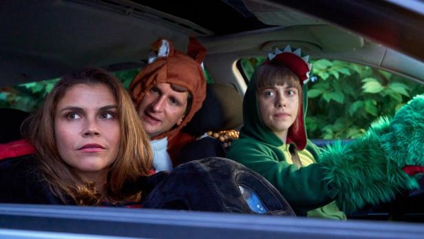 Drei Personen in Tierkostümen sitzen in einem Auto.