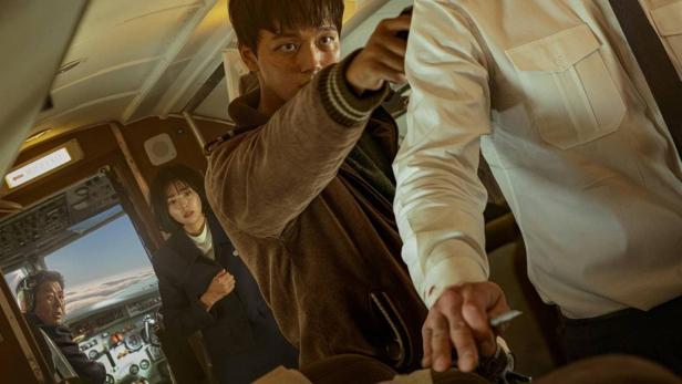 Auf dem Filmplakat zu „Hijacking“ bedroht ein Mann in einem Flugzeug den Piloten.