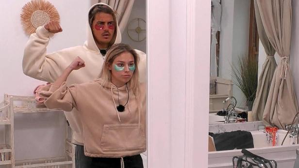 Ein Paar mit Augenmasken posiert muskulös vor einem Spiegel.