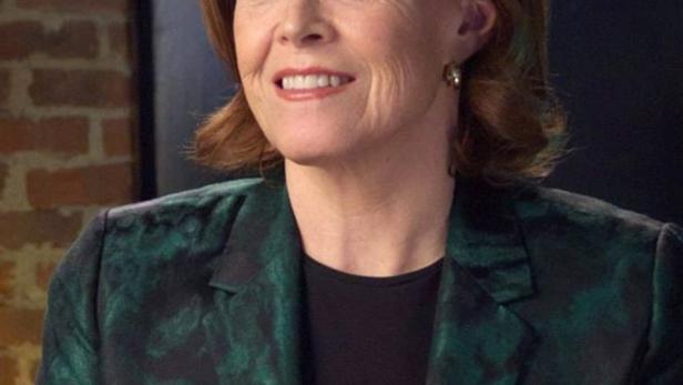 Sigourney Weaver trägt einen grünen Blazer vor einer Ziegelwand.
