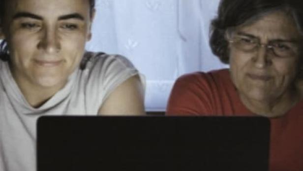 Eine junge und eine ältere Frau sitzen vor einem Laptop.