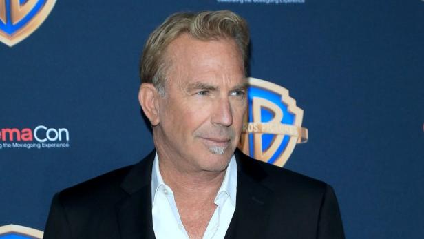 Ein Porträt von Kevin Costner vor einem Warner Bros. Pictures-Logo.