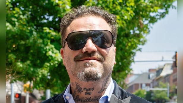 Ein Porträt von Bam Margera mit Sonnenbrille und Tätowierungen am Hals.