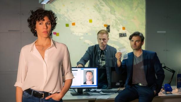 Drei Personen in einem Büro, möglicherweise bei einer polizeilichen Ermittlung.