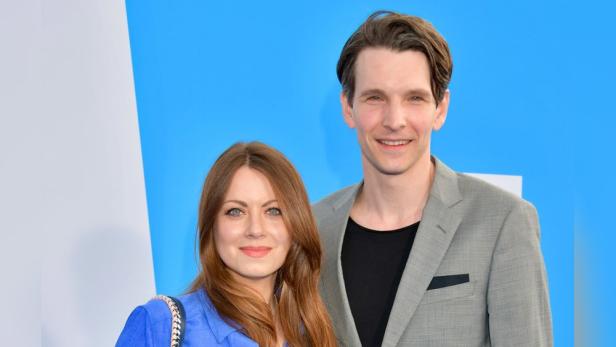 Alice Dwyer und Sabin Tambrea posieren zusammen vor einem blauen Hintergrund.