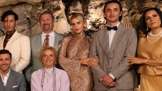 Eine festlich gekleidete Gruppe von Menschen posiert vor einer Felswand.