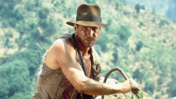 Harrison Ford als Indiana Jones mit Peitsche vor grünem Hintergrund.