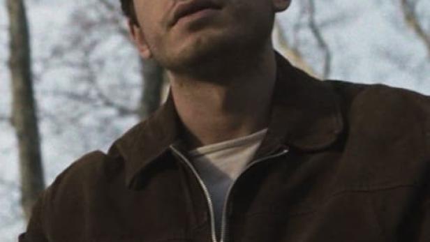 Ein Mann mit brauner Jacke blickt in den Himmel.