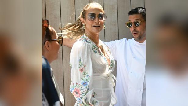 Jennifer Lopez mit einem Koch in einem weißen, geblümten Kleid.