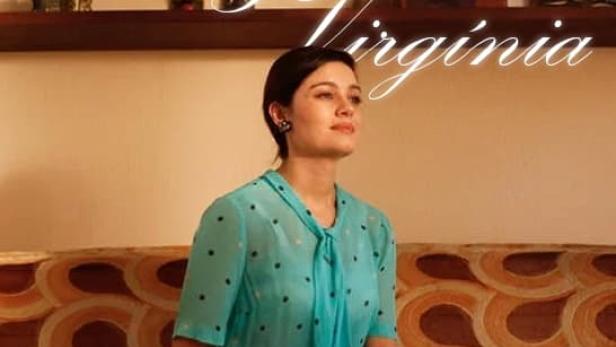 Eine Frau im türkisfarbenen Kleid sitzt vor dem Filmtitel „Adelaide & Virginia“.