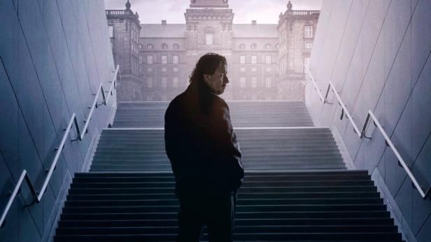 Das Filmplakat für „Mørkeland“ zeigt einen Mann auf einer Treppe mit Blick auf ein Gebäude.
