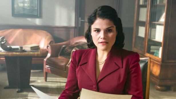 Aenne Burda in einem roten Blazer hält ein Dokument in der Hand.