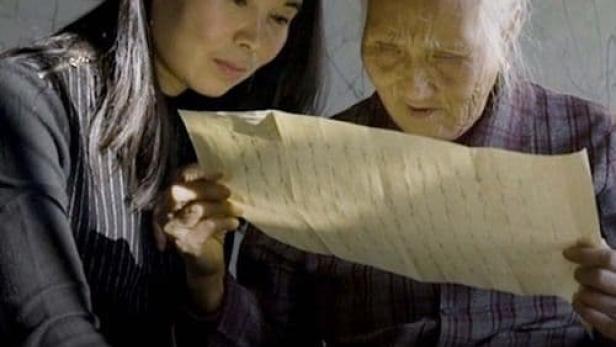 Zwei Frauen betrachten ein Schriftstück mit Nüshu-Zeichen.