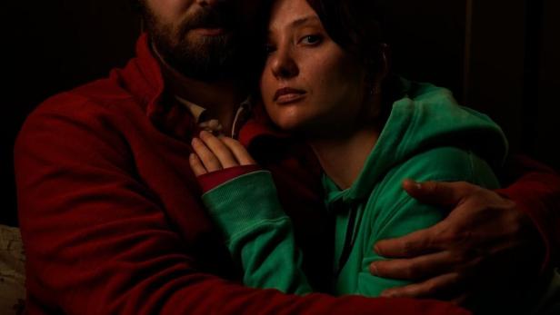 Ein Mann mit Brille umarmt eine Frau mit grünem Kapuzenpullover.