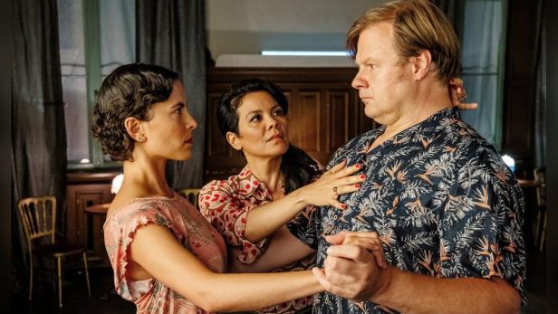 Zwei Frauen tanzen Tango mit einem Mann.