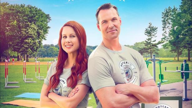 Das Filmplakat für „Love at the Boot Camp“ mit Leanne Lapp und Daniel Cudmore vor einer Trainingskulisse.