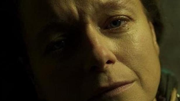 Nahaufnahme des Gesichts einer Frau mit ernstem Ausdruck.