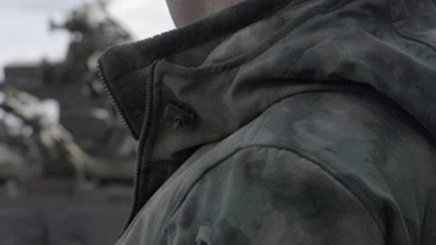 Ein Soldat mit Mütze und Tarnjacke, auf der ein Abzeichen mit russischer Flagge und Sowjetstern zu sehen ist.