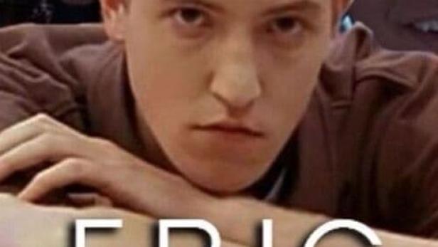 Ein junger Mann namens Eric lehnt auf einem Stapel Bücher.