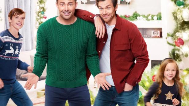 Das Filmplakat für „The Holiday Sitter“ zeigt zwei Männer und zwei Kinder vor einem Weihnachtsbaum.