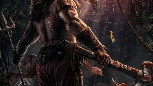 Ein Krieger mit Axt und Dreizack steht vor einer apokalyptischen Szene für den Film „Kantara“.