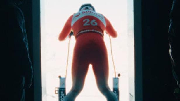 Ein Skirennläufer mit der Nummer 26 steht am Start und blickt auf die Piste.