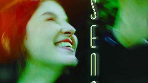 Eine lächelnde junge Frau vor dem Schriftzug „Absence“.