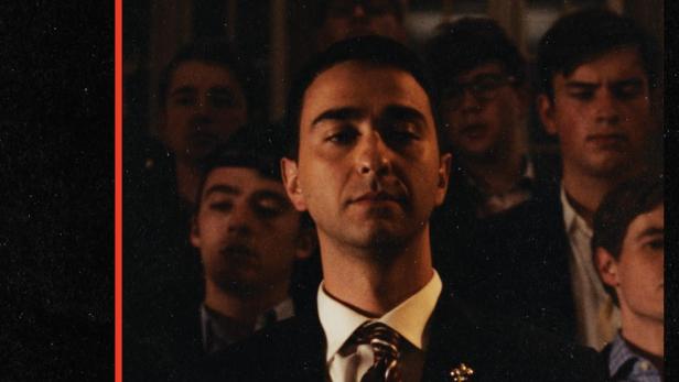 Ein Mann im Anzug steht vor einer Gruppe von Menschen; Titel „The Line“ im Hintergrund.